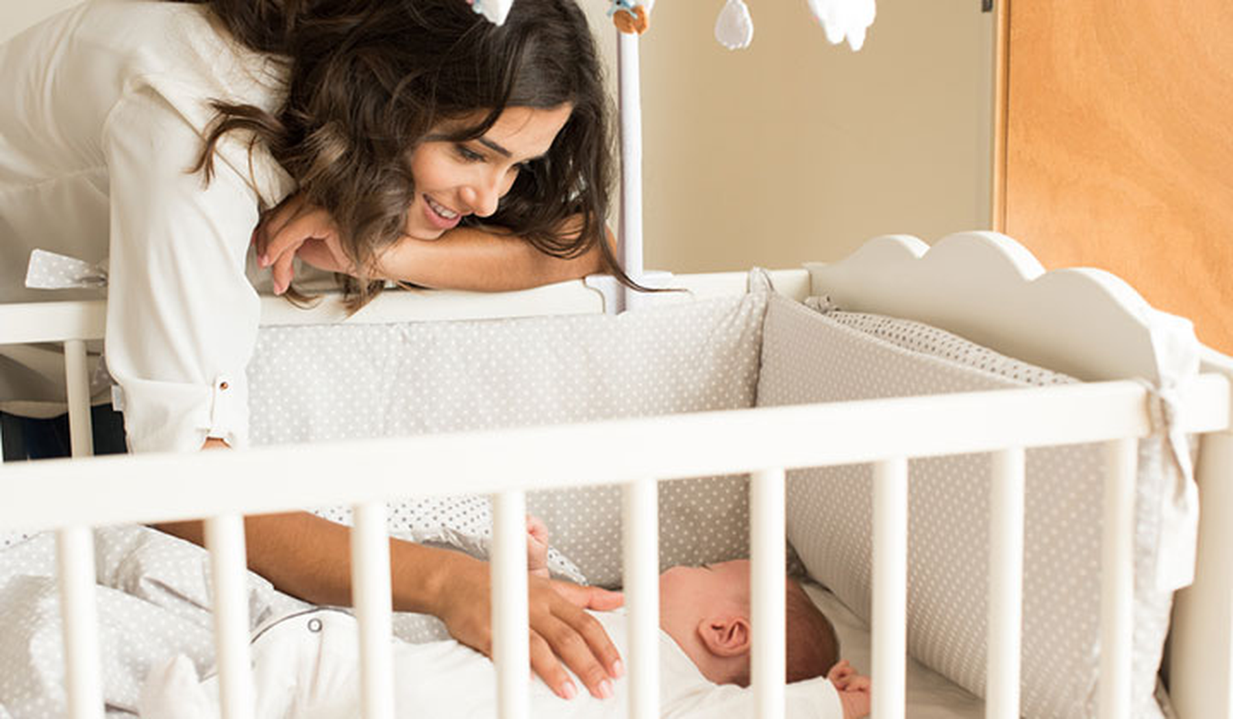 Woman smiling over sleeping baby in a crib