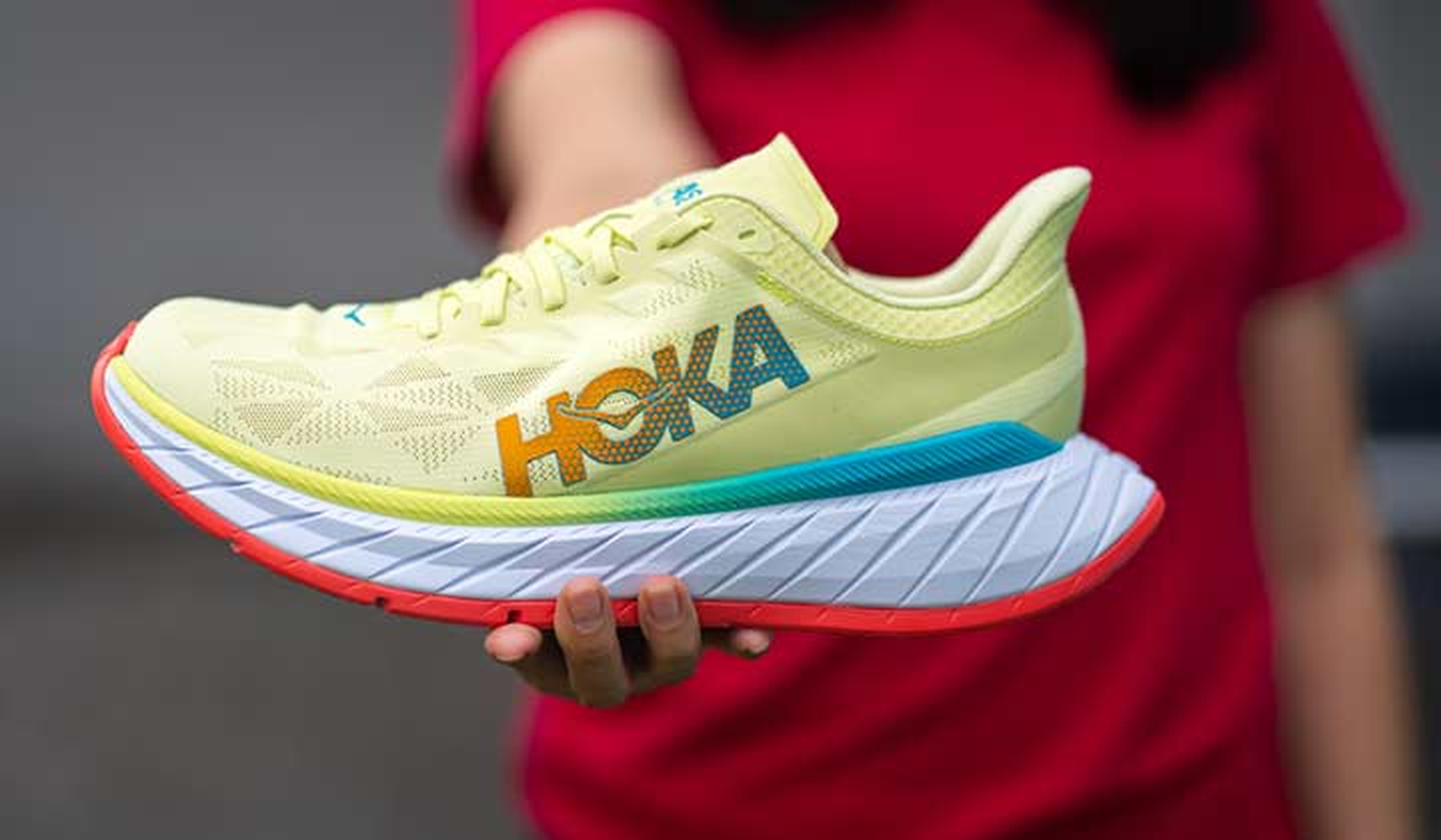 Woman holding yellow Hoka sneaker
