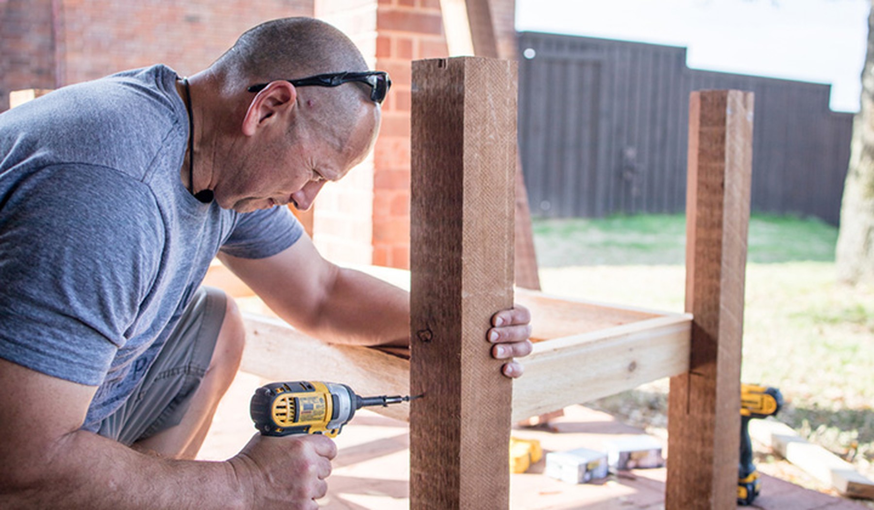 Man using tools to build a deck outside