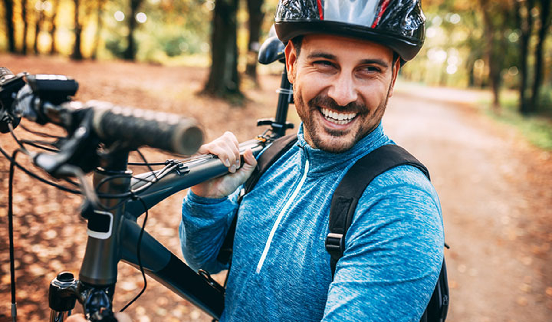 Smiling young man carrying a mountain bike