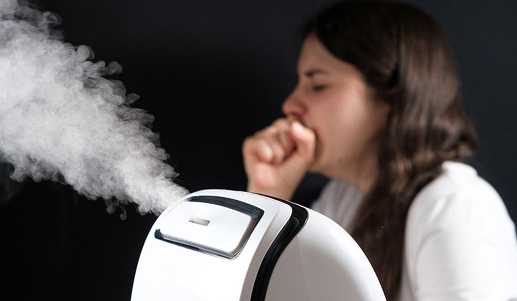 Young woman coughing with a humidifier in front of her