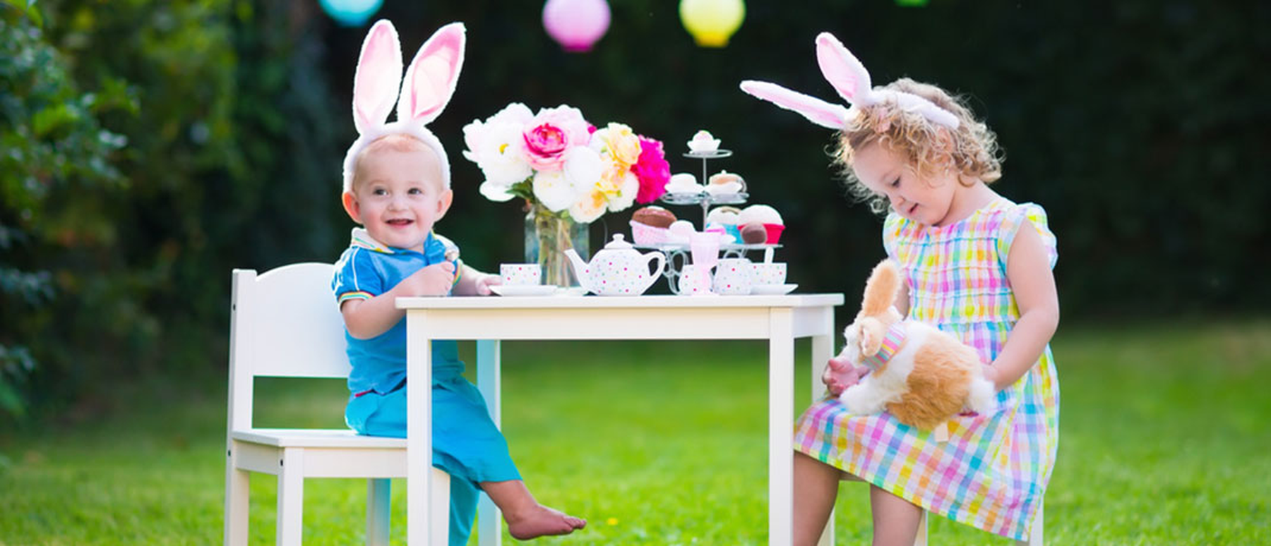 Little kids wearing bunny ears sitting at a table outside
