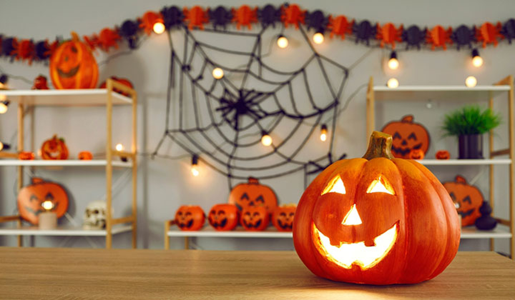 Halloween decor with a yarn spider web, jack o lanterns and black and orange garland