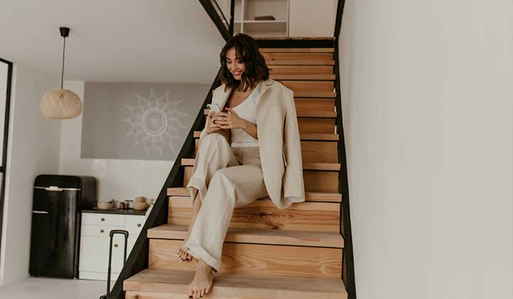 Young smiling woman wearing linen separates sitting on the stairs in her home