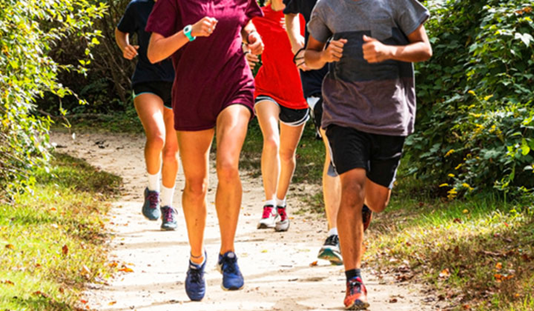 Male and female cross country runners on a trail