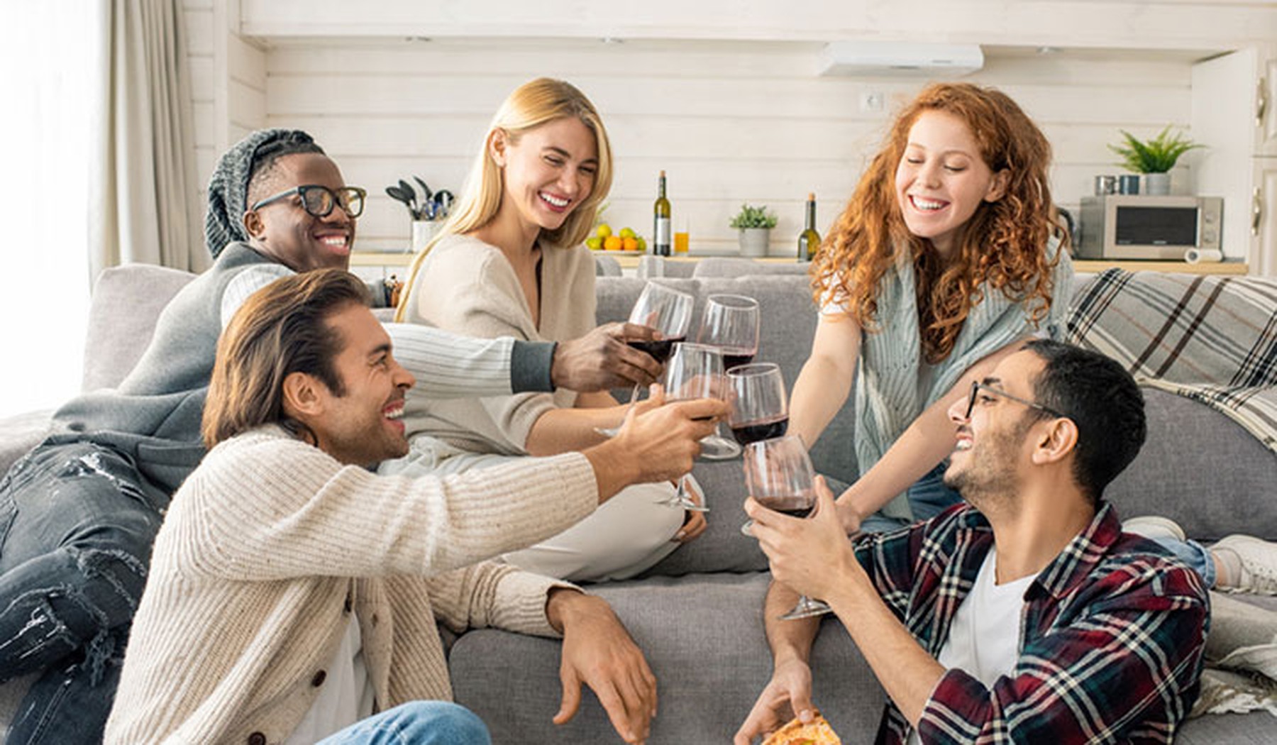 Young group of people toasting with wine glasses in a living room