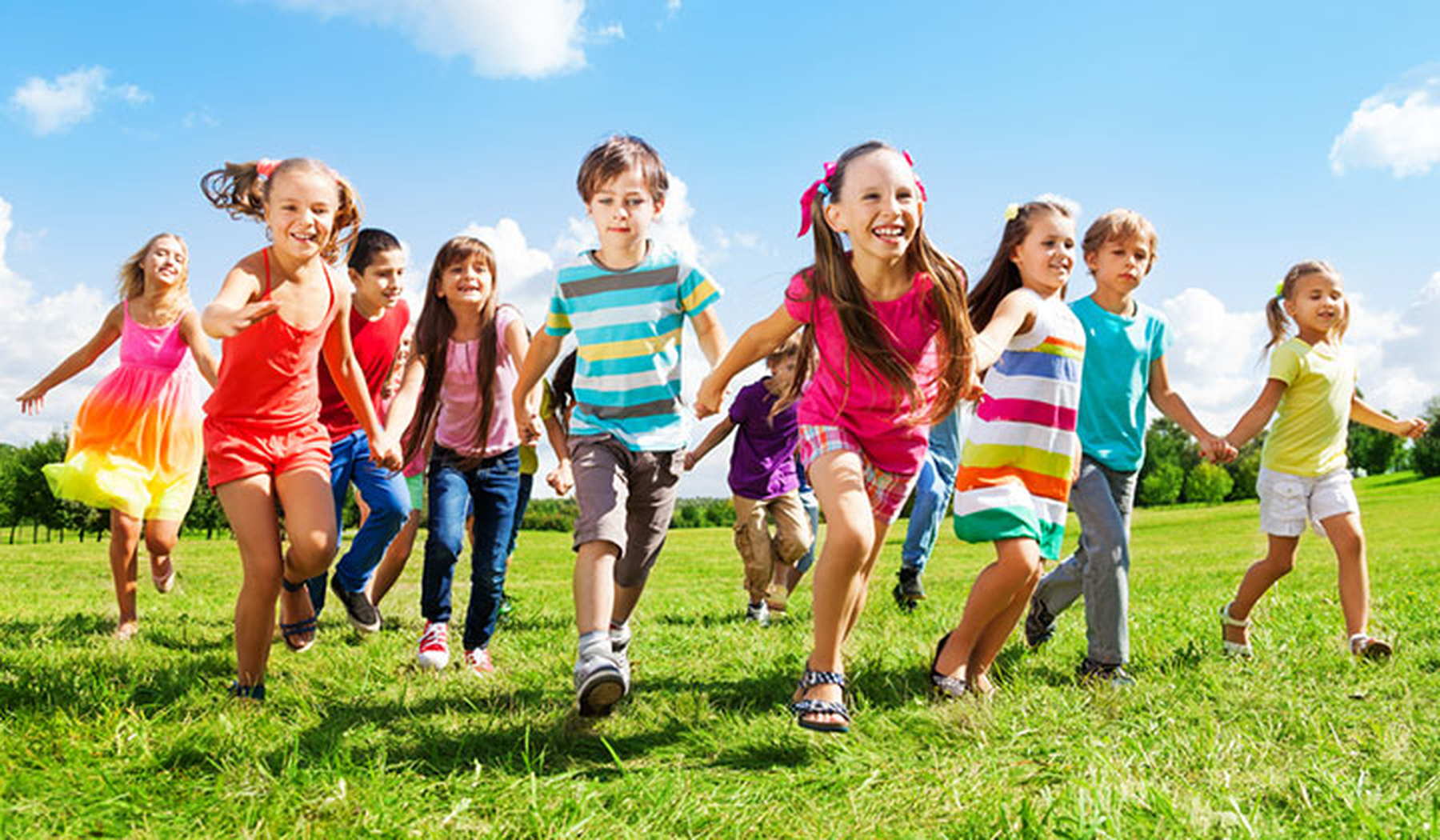 Happy kids running outside in a green field