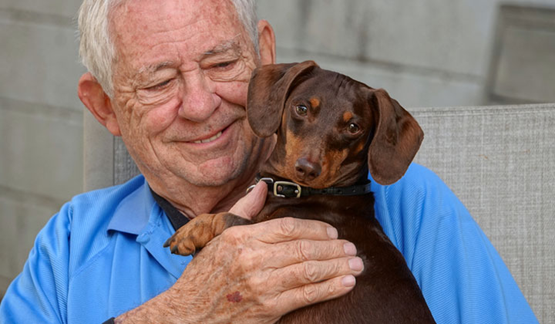 Older man hugging his doxie dog