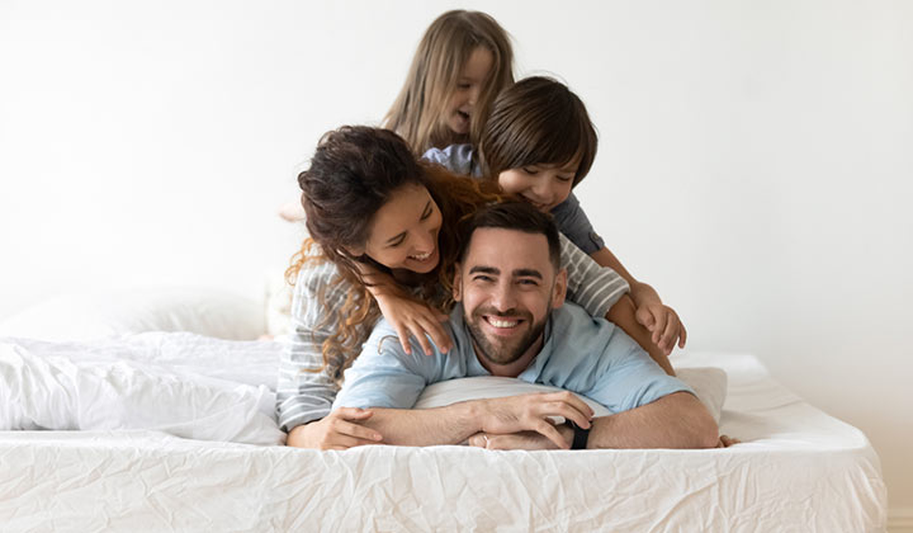 Smiling family piled on a bed