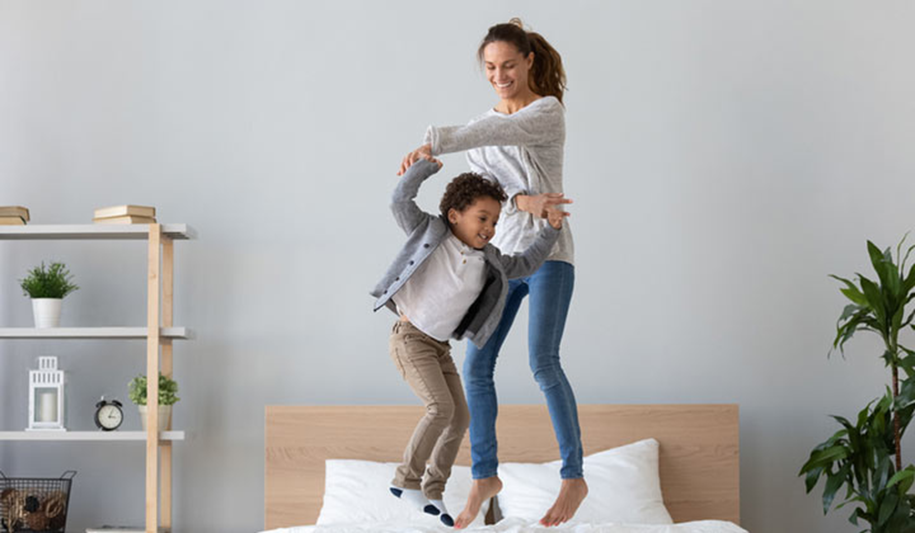 Happy mom and son jumping on a bed