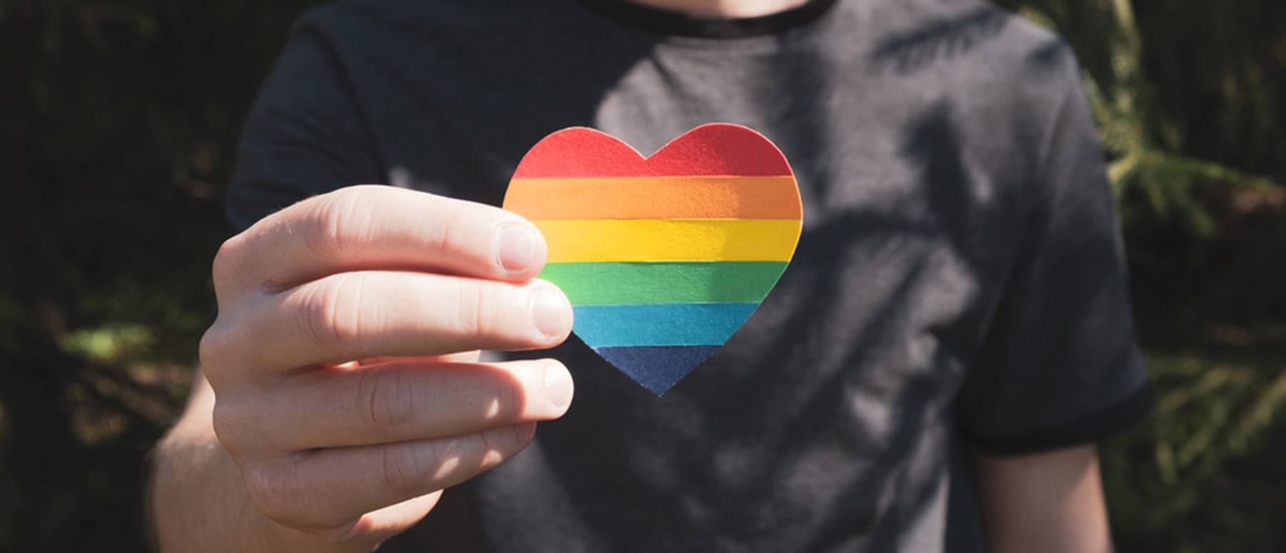Man holding a rainbow paper heart