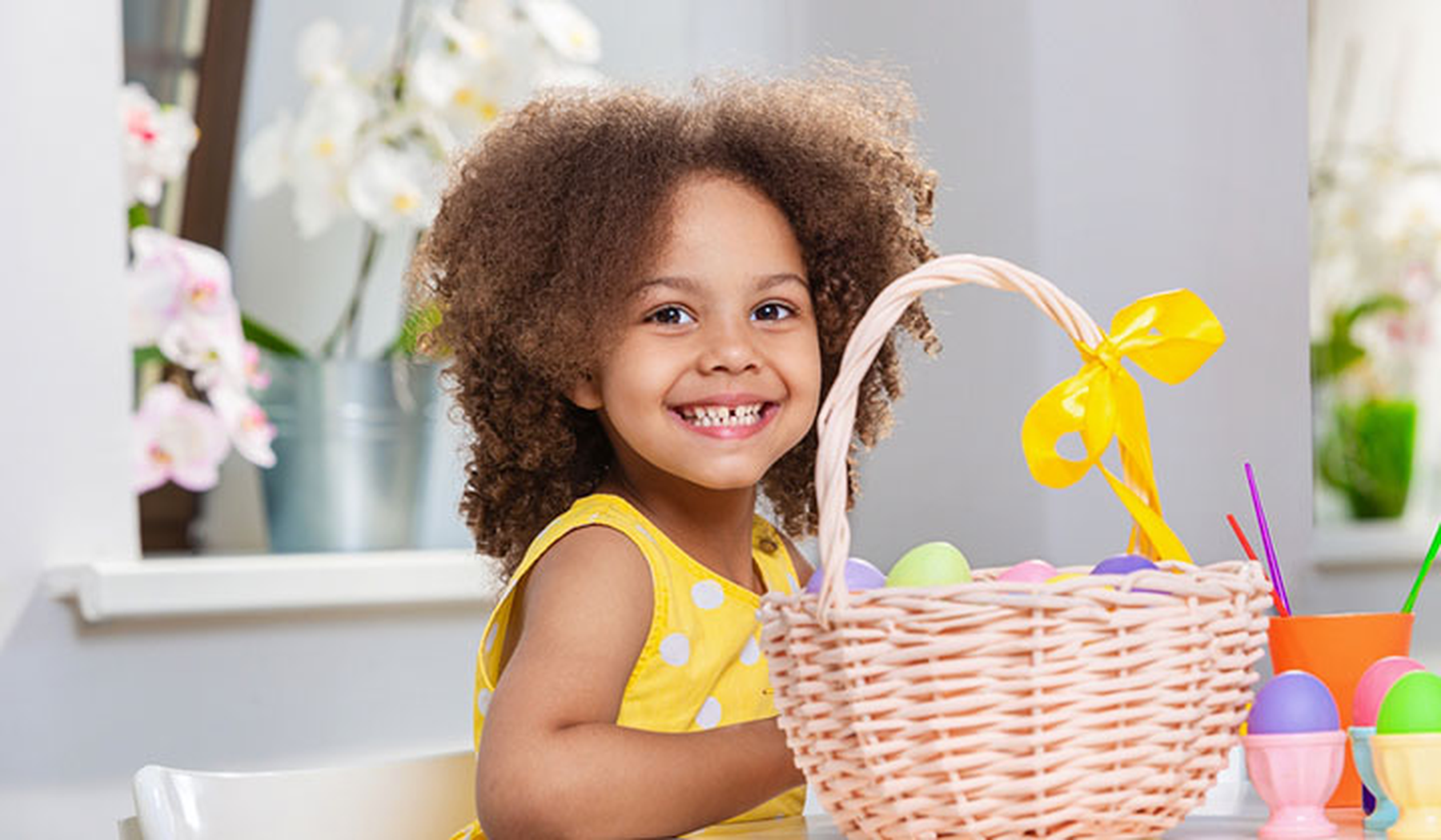 Smiling girl in yellow dress with an Easter basket