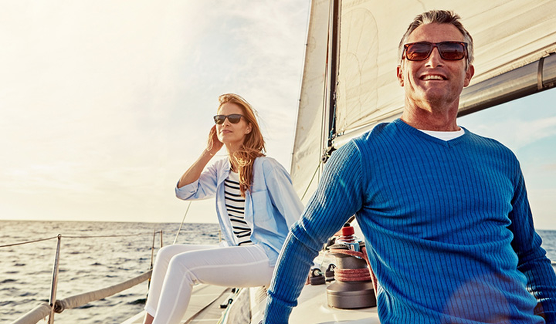 Man and woman wearing sunglasses on a sailboat
