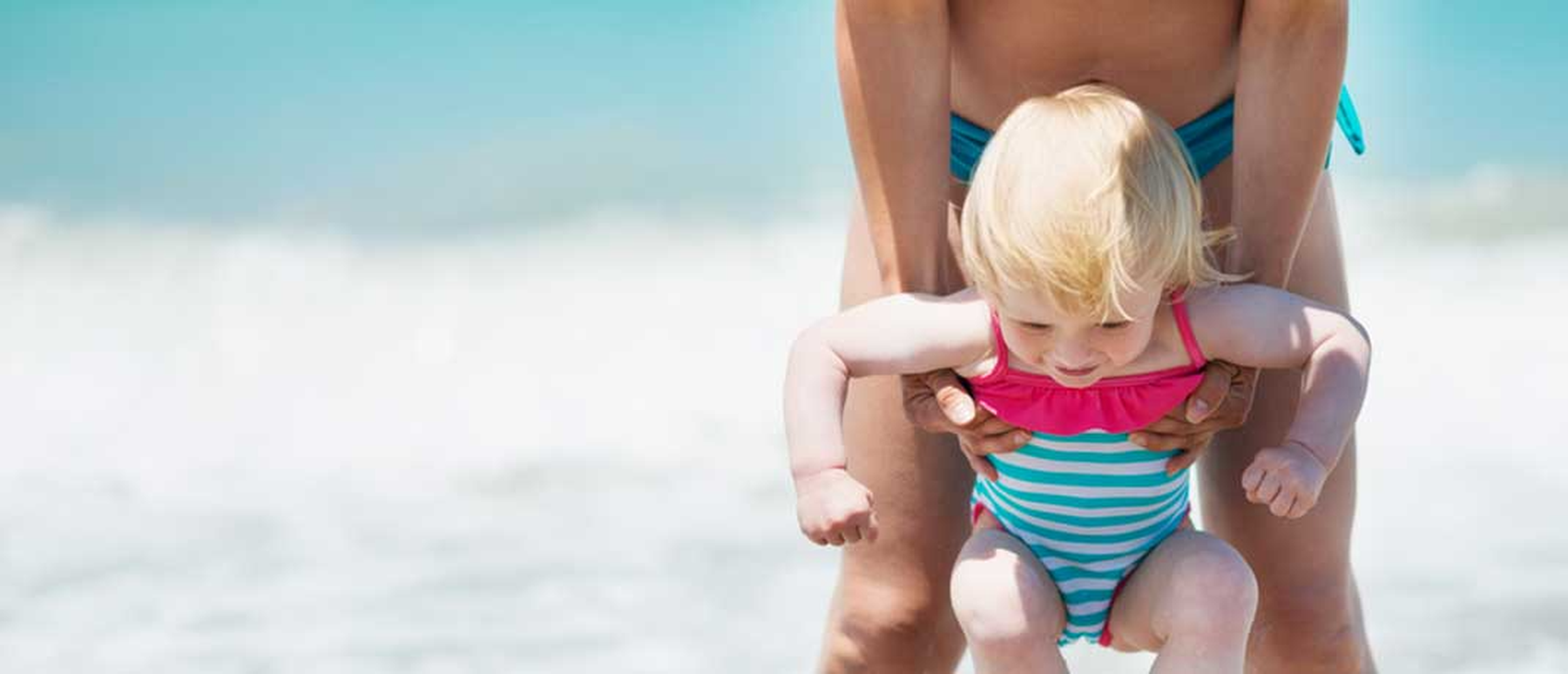 Baby and mom in swimsuits at the beach