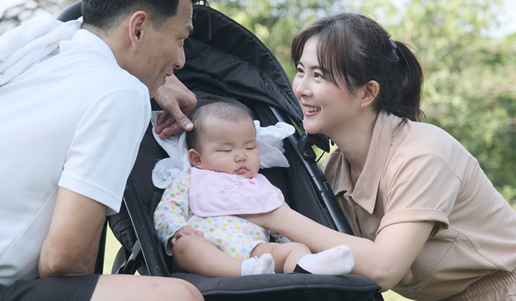 Parents smiling over their baby in a stroller