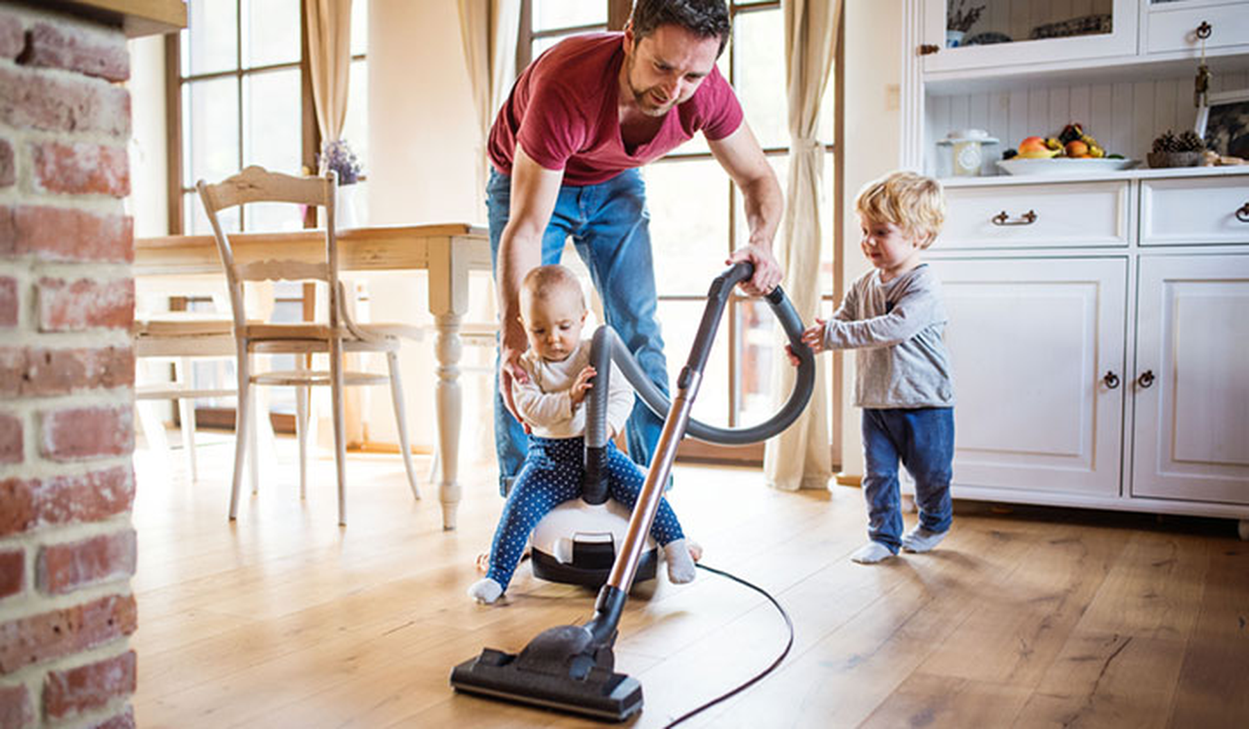 Dad and two young kids vacuuming