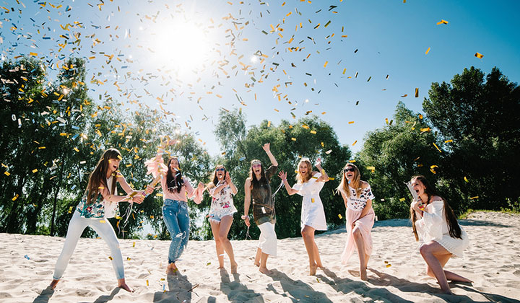Young women throwing confetti on the beach