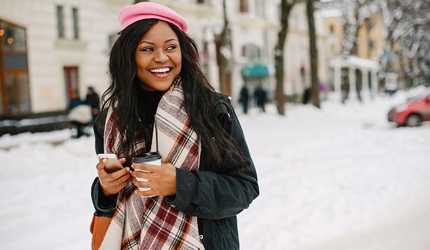 Smiling young woman in a pink hat and plaid scarf