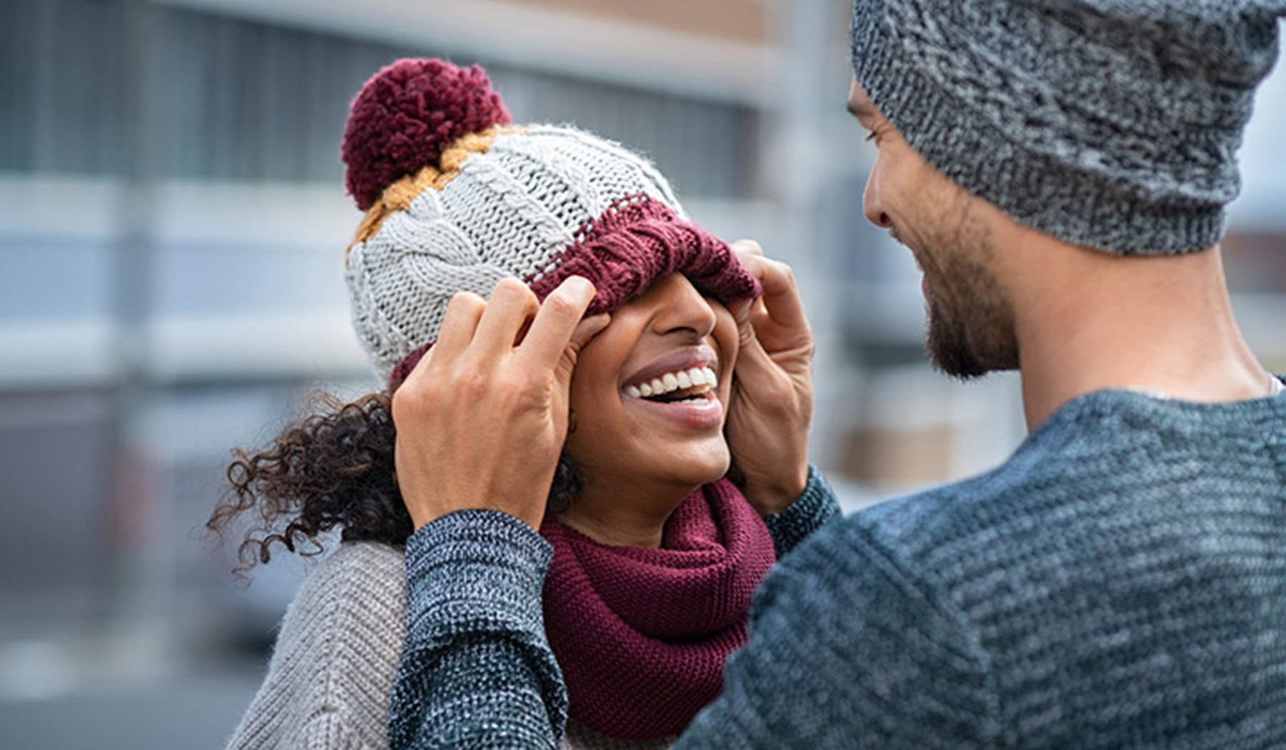 Young smiling couple fixing each other's knit hats 