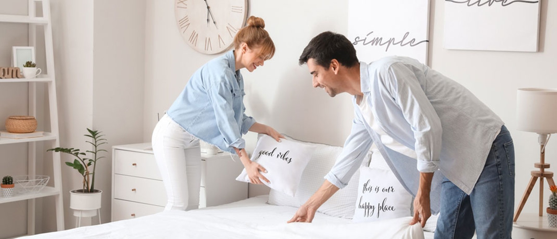 Young couple making bed together