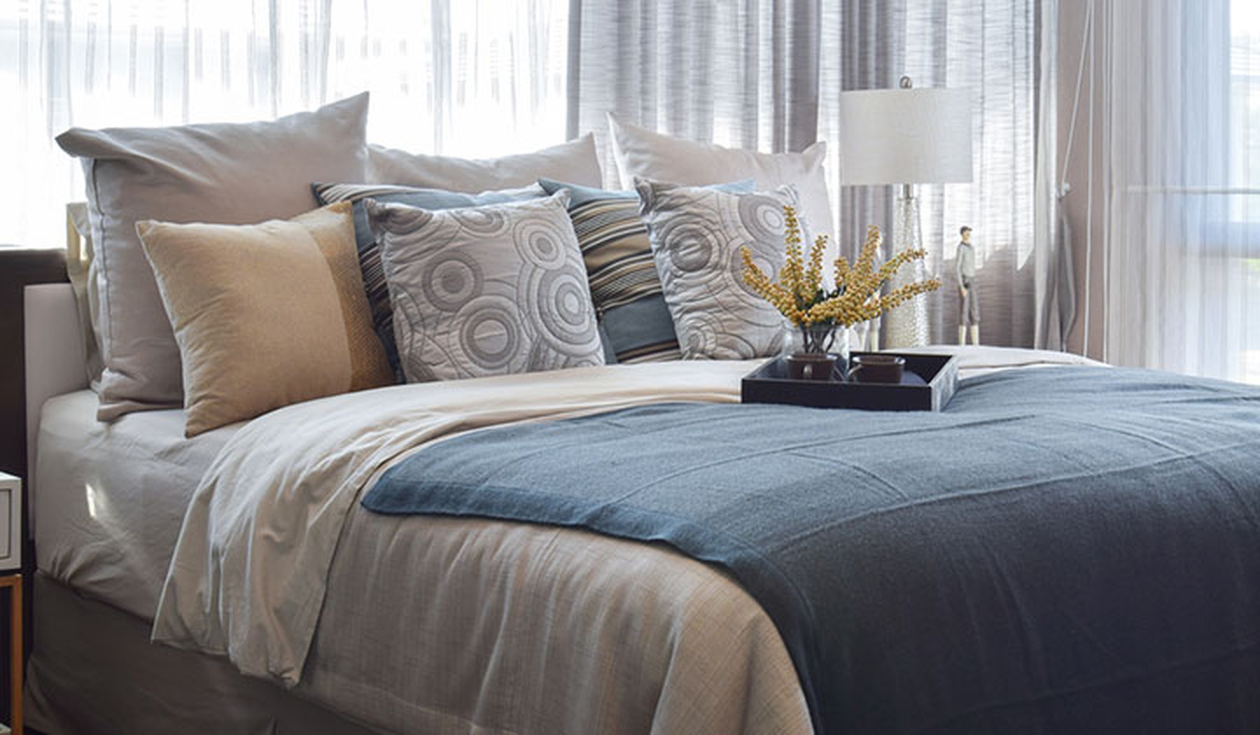 Bed with blue comforter and patterned throw pillows 