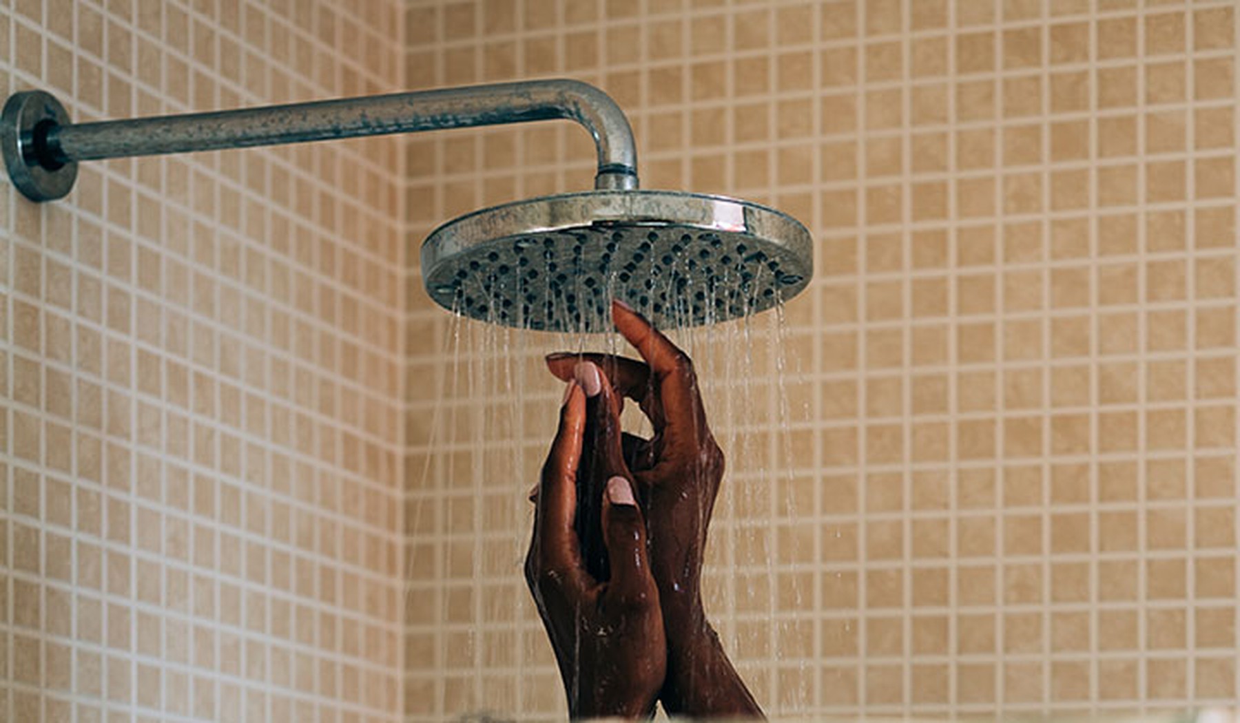 Woman raising her hands to the shower head