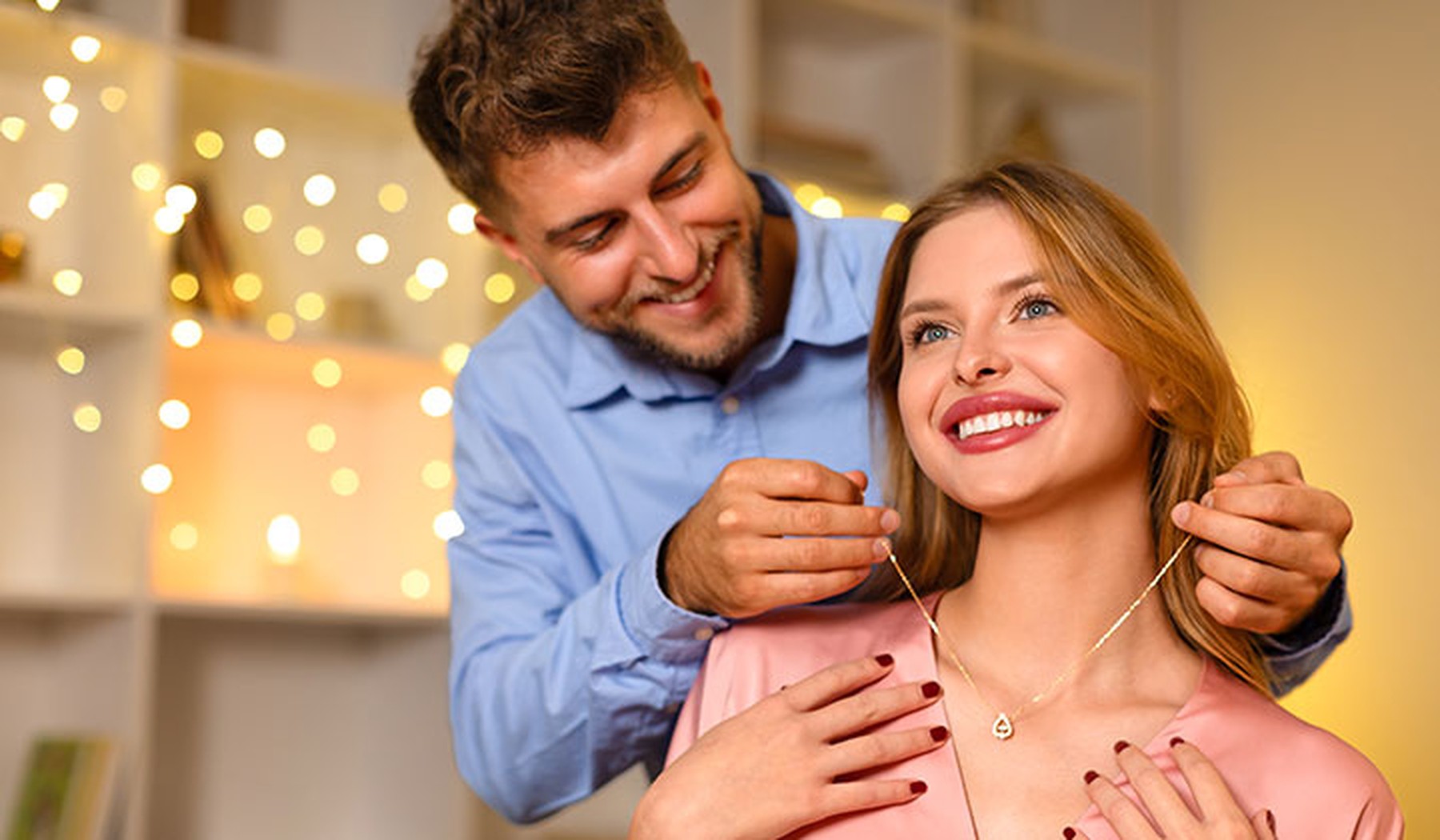 Man putting heart necklace on smiling woman